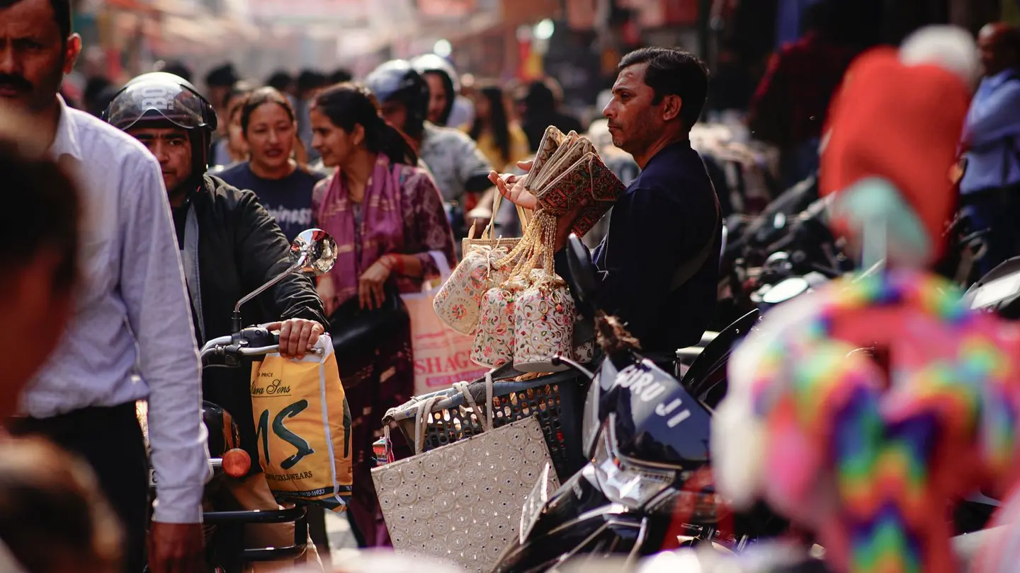 Bustling street market scene with shoppers and vendors.