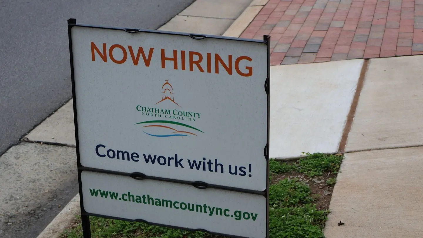 A Now Hiring sign for Chatham County, North Carolina, beside a pavement